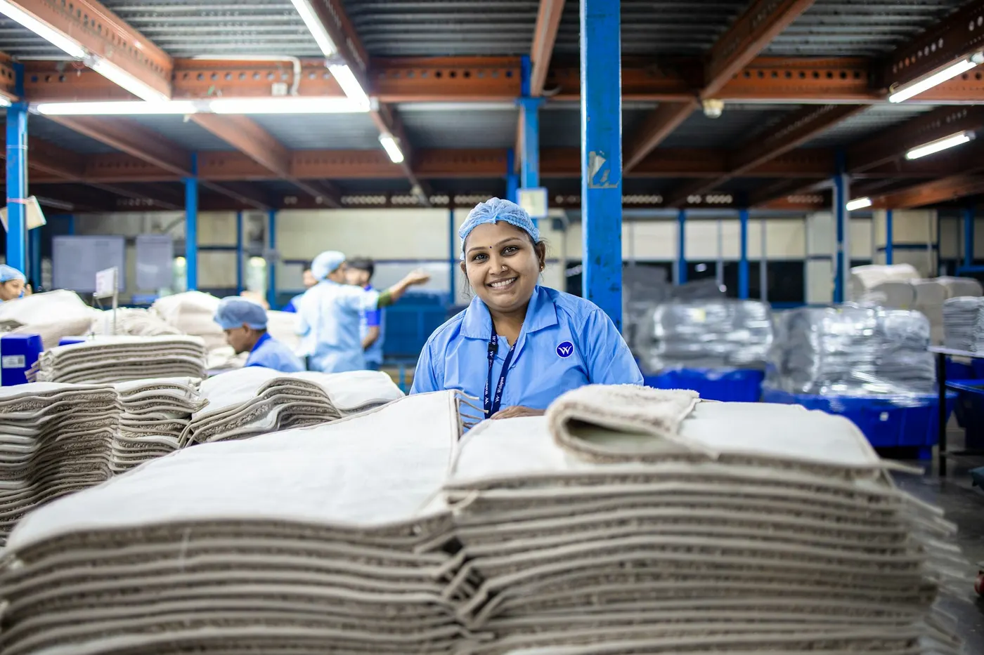 Une ouvrière en tenue de travail bleue sourit dans un atelier de production